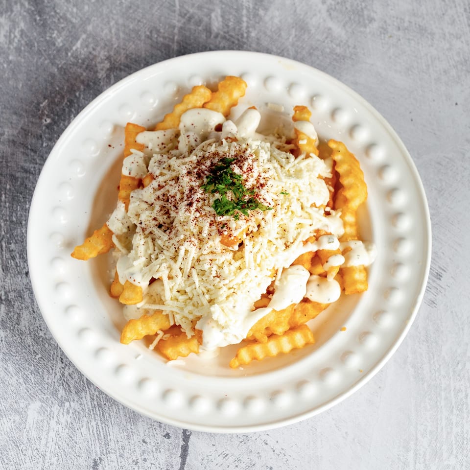 Crispy crinkle-cut fries topped with melted cheese, white sauce, and a sprinkle of herbs.
